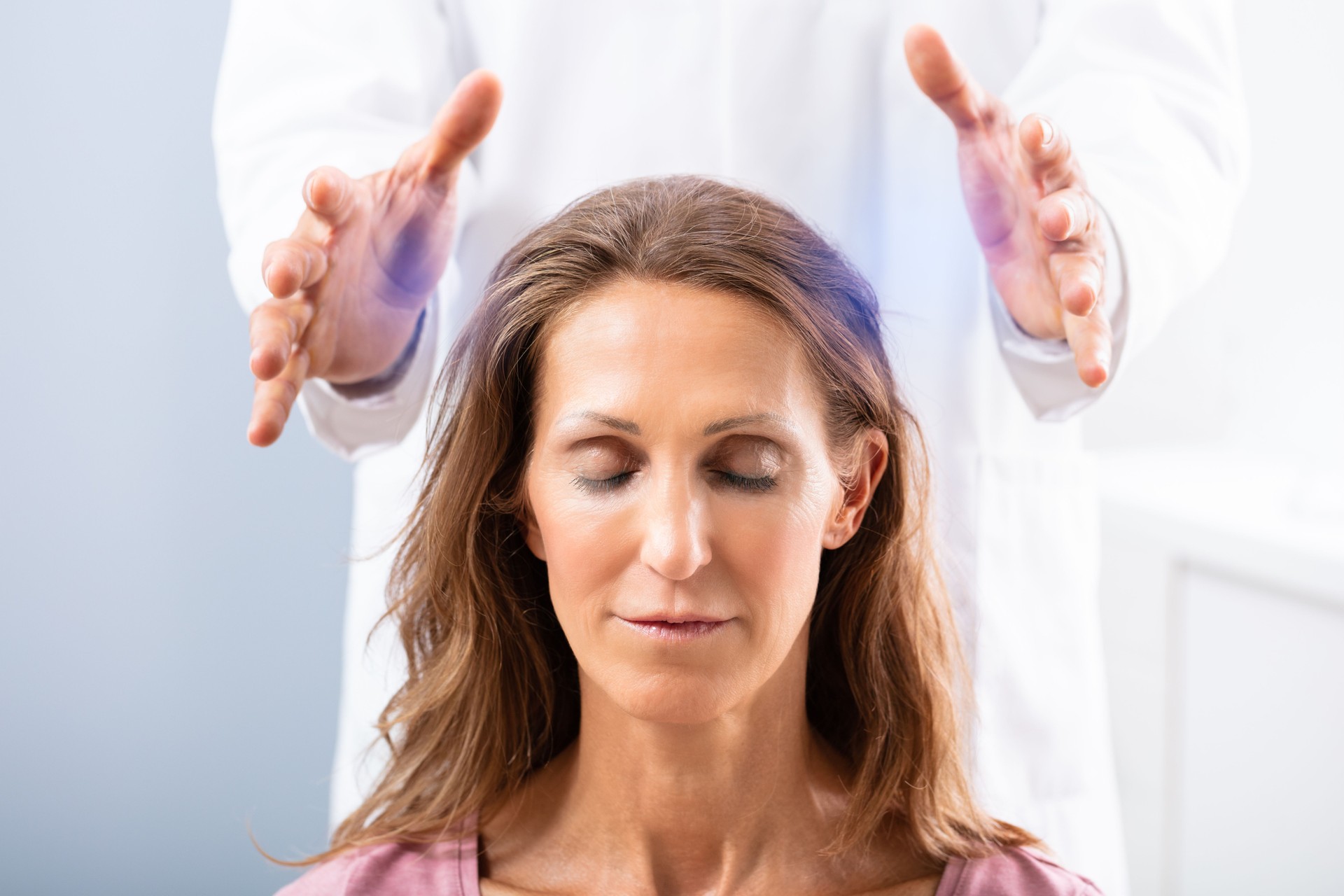 Therapist Giving Reiki Healing Treatment To Woman