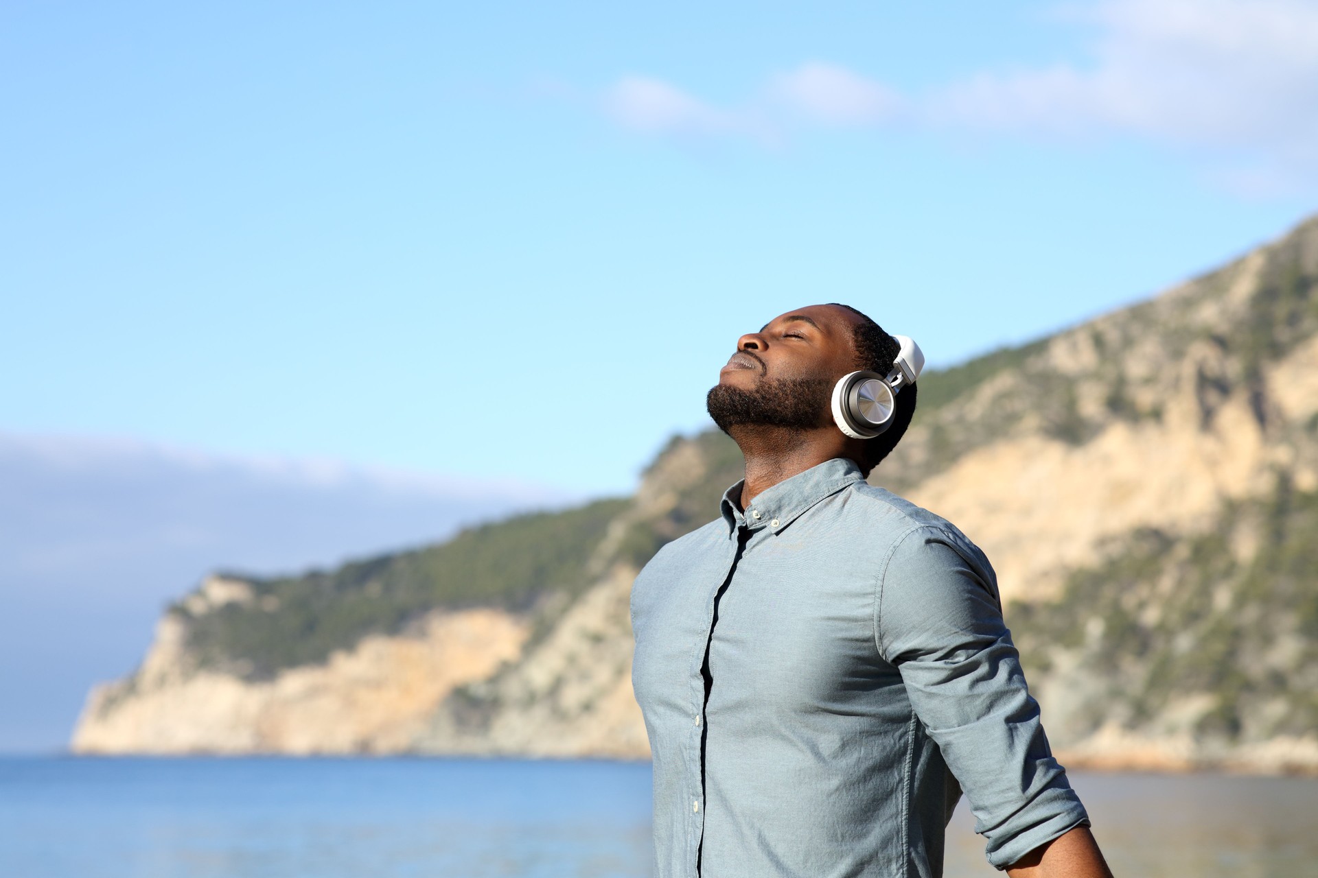 Black man meditating with headphones on the beach